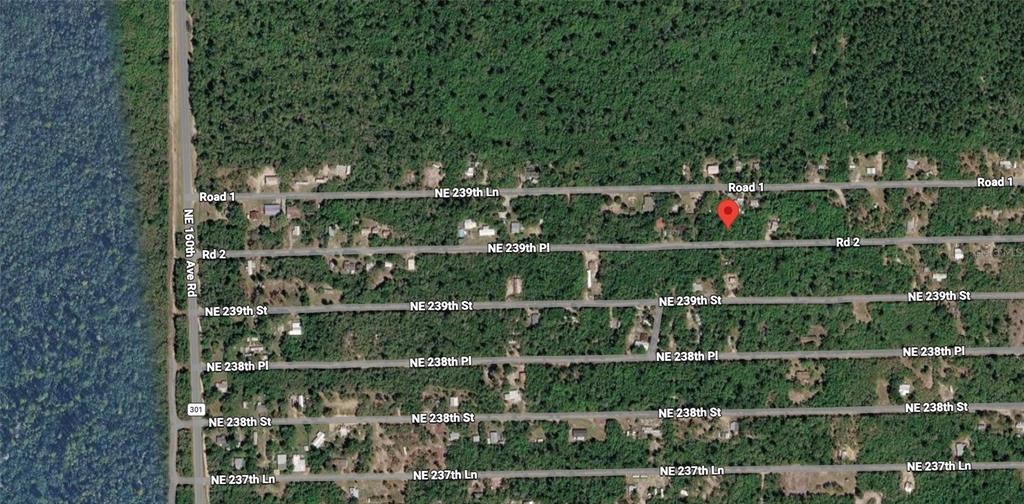 This is an aerial map view of a residential area with a red location pin — NE 239TH PL, FORT MC COY, FL