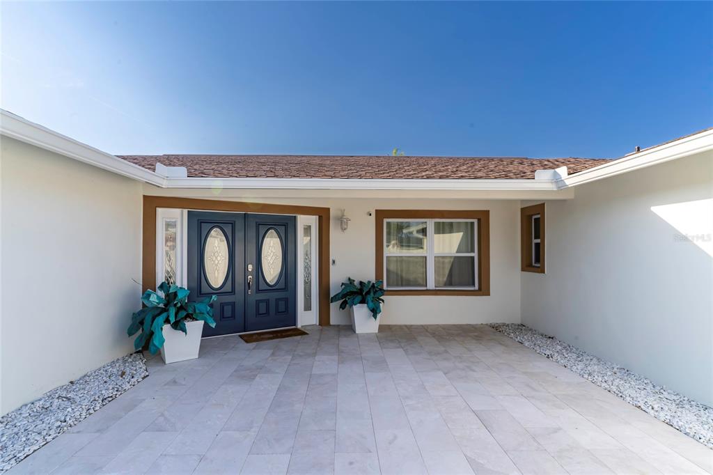 A paved entryway leads to a blue double front door with oval glass inserts — 320 HARBOR PASSAGE, CLEARWATER BEACH, FL