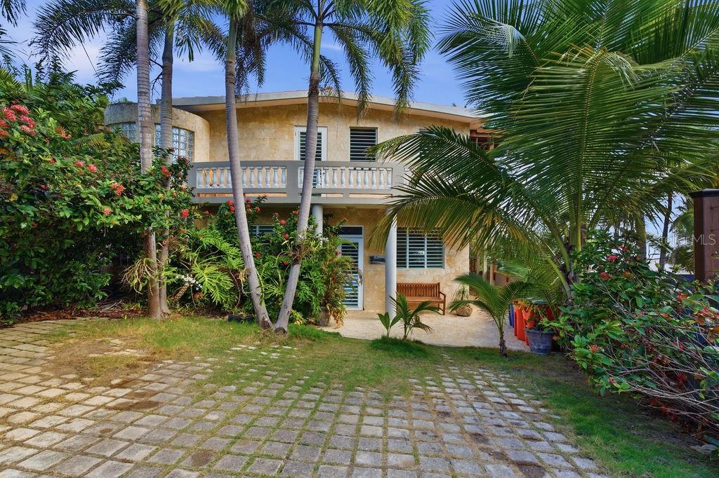 A two-story house with a balcony, palm trees, and a stone-paved driveway — 26 BARRIO PUNTAS SANDY BEACH, RINCON, PR