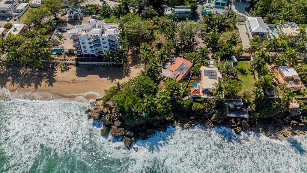 An aerial view shows coastal homes, a sandy beach, and rocky cliffs along the ocean — 26 BARRIO PUNTAS SANDY BEACH, RINCON, PR
