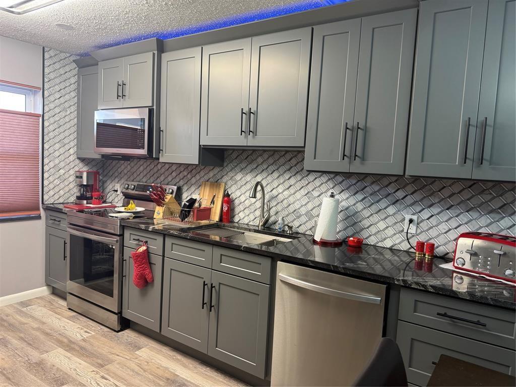 A kitchen with gray cabinets, stainless steel appliances, black countertops, and a diagonal tile backsplash — 25 SE 13th Street # B2, Boca Raton FL 33432, BOCA RATON, FL