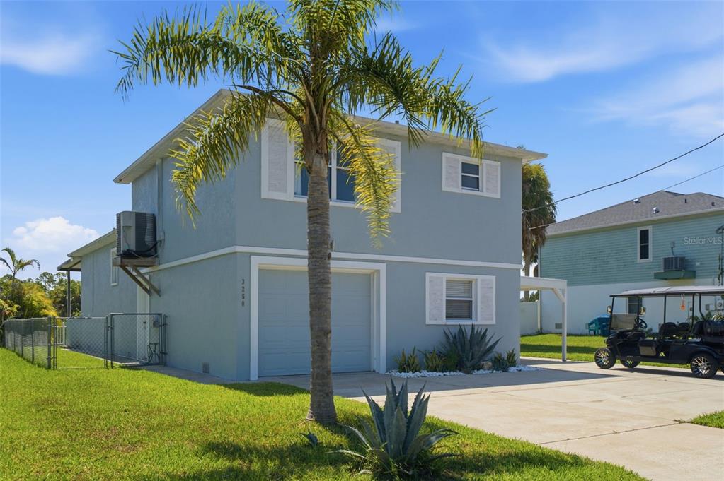 A two-story light blue house with a garage, a palm tree, and a golf cart — 3250 ROSE ARBOR DRIVE, HERNANDO BEACH, FL