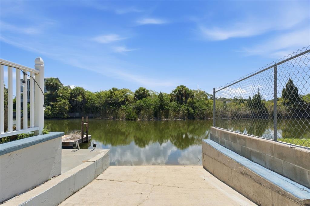 A concrete boat ramp leads into a calm canal bordered by trees and a fence — 3250 ROSE ARBOR DRIVE, HERNANDO BEACH, FL