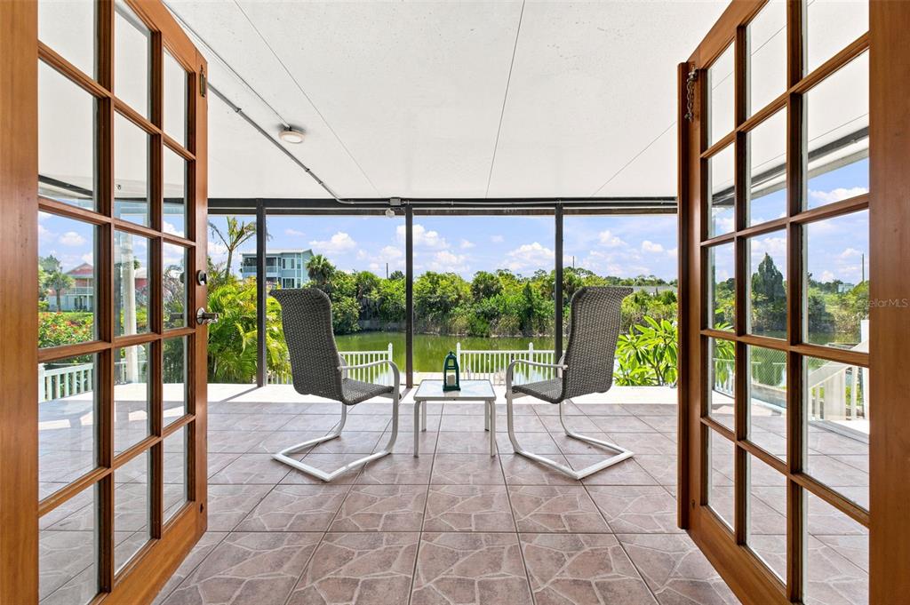 A covered patio with tiled flooring features two chairs and a table overlooking a pond — 3250 ROSE ARBOR DRIVE, HERNANDO BEACH, FL