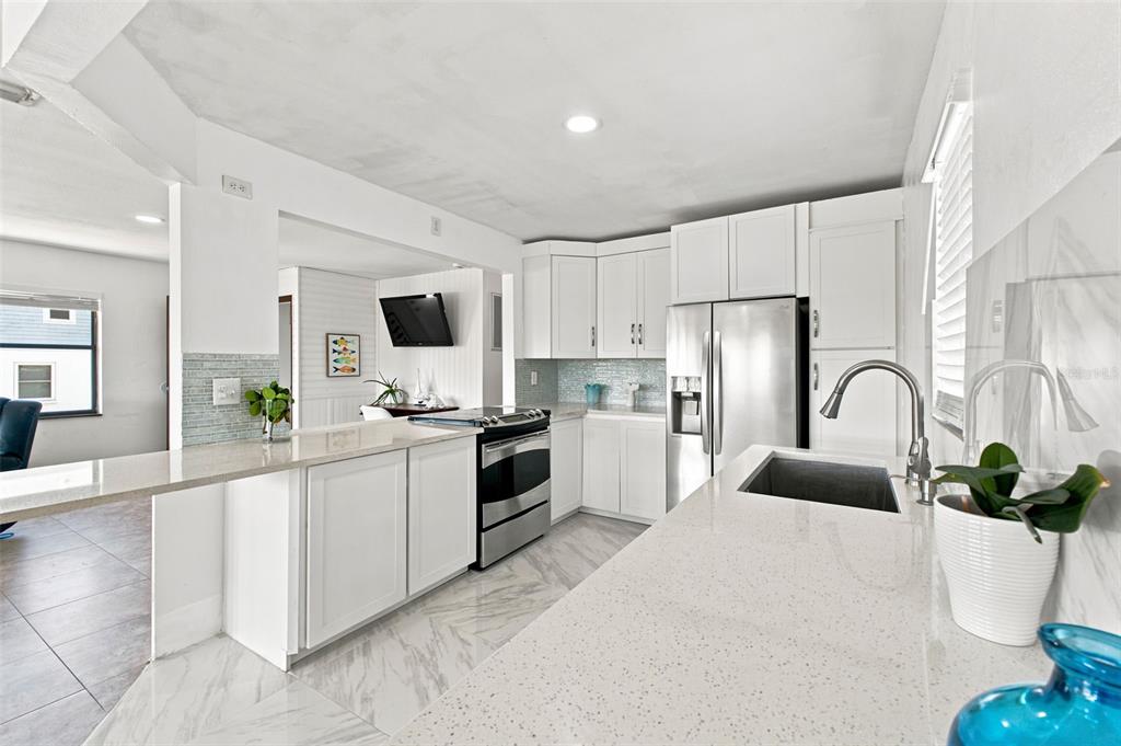 A modern kitchen features white cabinets, quartz countertops, stainless steel appliances, and light tile flooring — 3250 ROSE ARBOR DRIVE, HERNANDO BEACH, FL