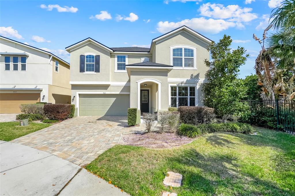A two-story suburban house features a paved driveway, a two-car garage, and light-colored stucco siding — 9021 SUNSHINE RIDGE LOOP, KISSIMMEE, FL