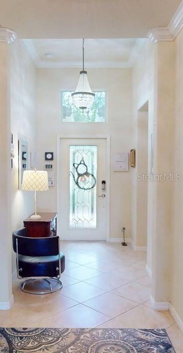 A foyer features tile flooring, a chandelier, a front door with glass, and a chair — 2571 LAURENTINA LANE, CAPE CORAL, FL