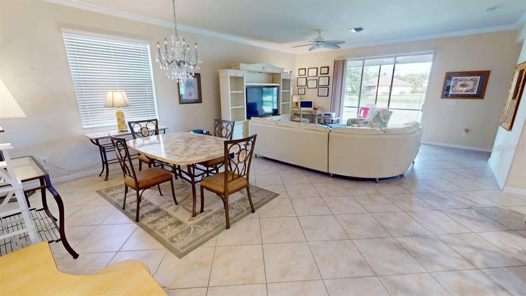 A living and dining area features tile floors, a chandelier, and a large sectional sofa — 2571 LAURENTINA LANE, CAPE CORAL, FL