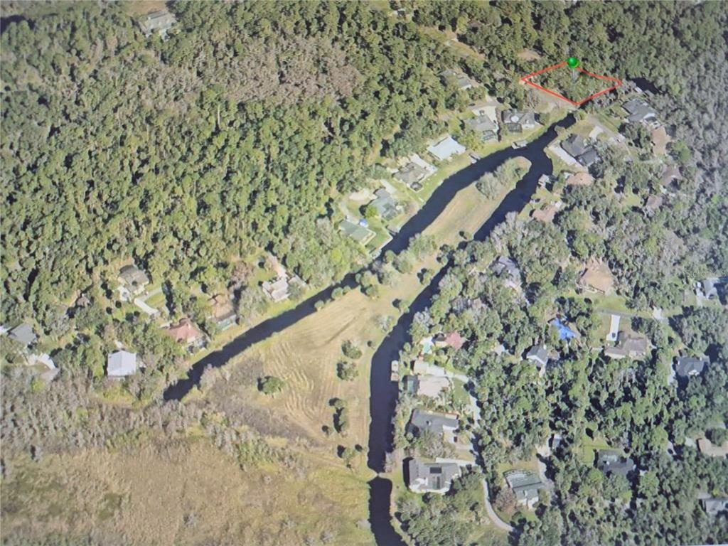 An aerial view shows a residential lot outlined in red within a wooded neighborhood — 327 HARBOR TRAIL, DELTONA, FL