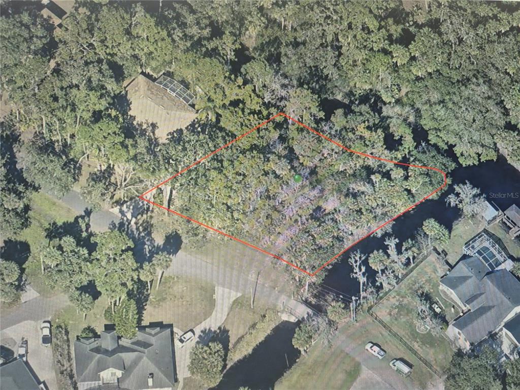 An aerial view shows a wooded, undeveloped residential lot outlined in red — 327 HARBOR TRAIL, DELTONA, FL