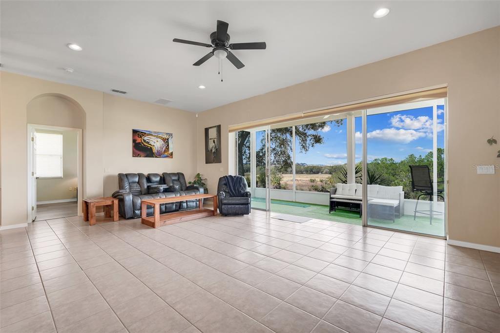 A spacious living room with tile floors, a ceiling fan, and large sliding glass doors — 2390 CALEDONIAN STREET, CLERMONT, FL