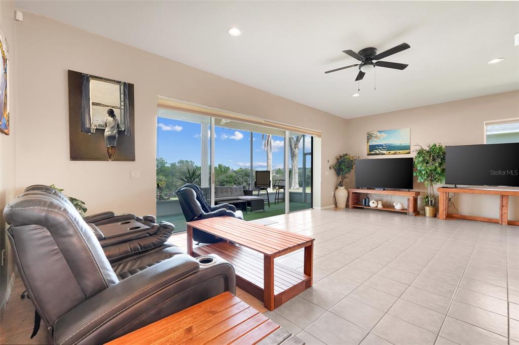 A living room features tile flooring, a ceiling fan, and sliding glass doors to a patio — 2390 CALEDONIAN STREET, CLERMONT, FL