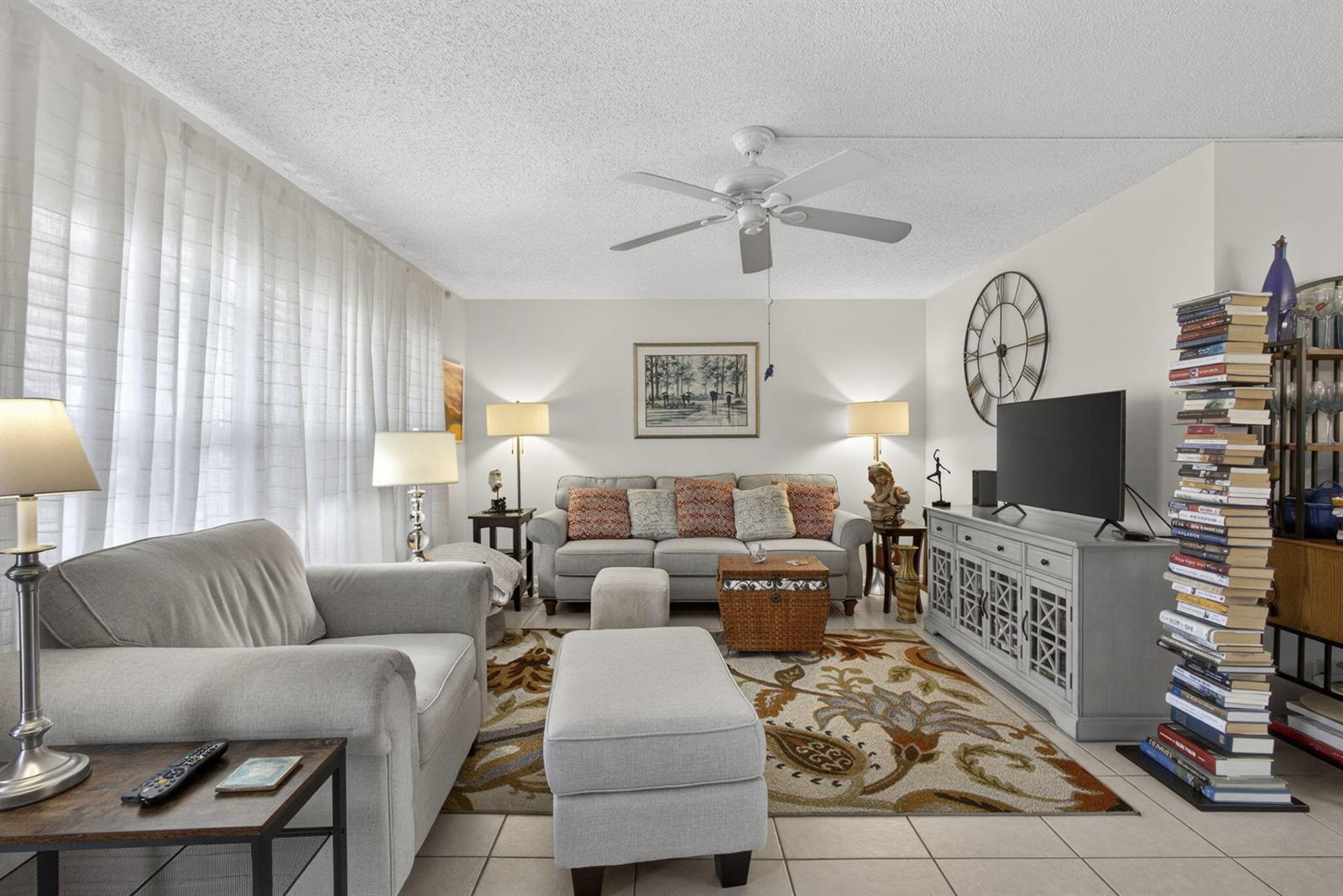 A living room features a grey sofa, matching ottoman, patterned area rug, and a tall bookshelf — 308 Greenbrier A, West Palm Beach FL 33417, WEST PALM BEACH, FL