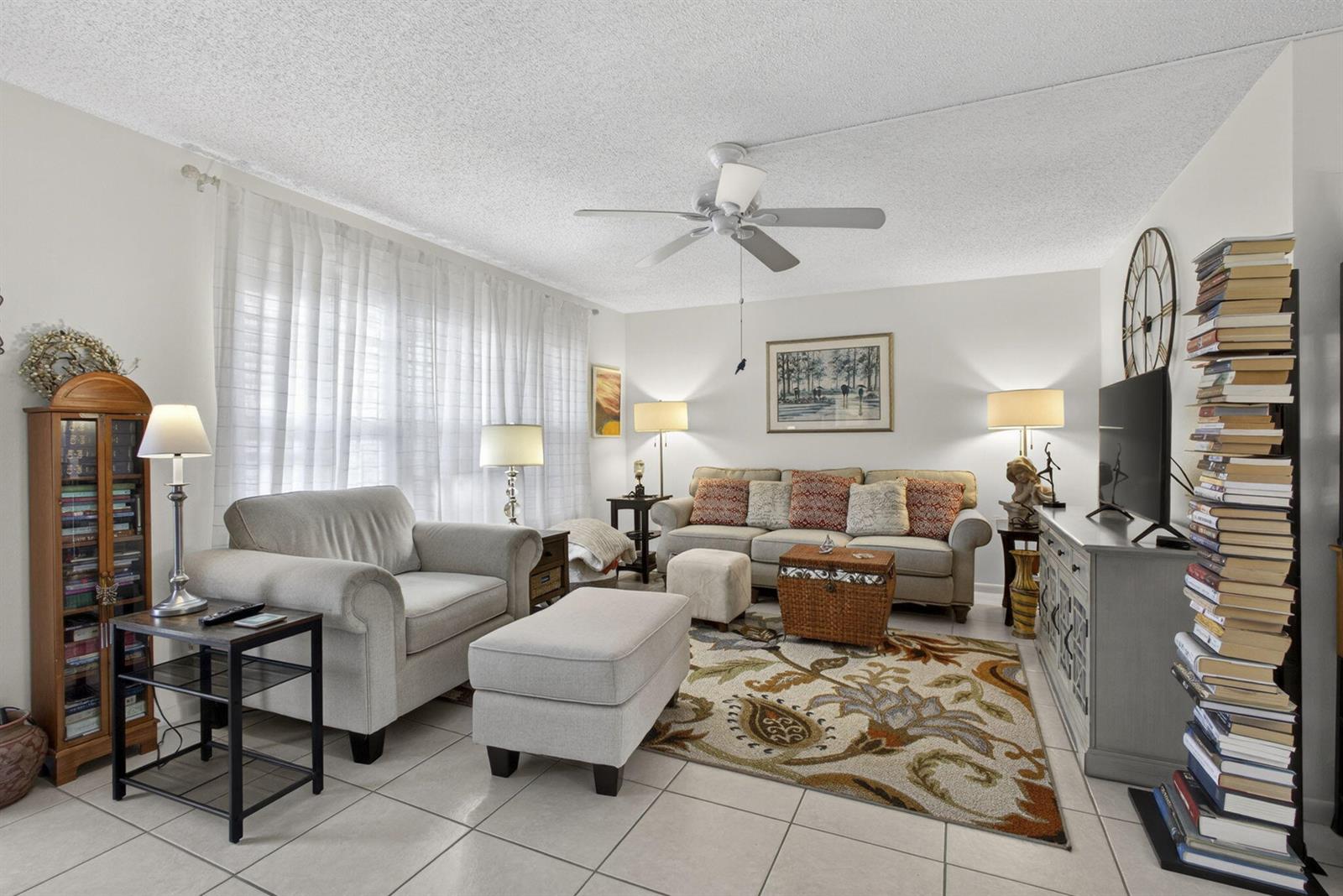 A living room features a beige sofa, an armchair, a patterned rug, and a tall bookshelf — 308 Greenbrier A, West Palm Beach FL 33417, WEST PALM BEACH, FL