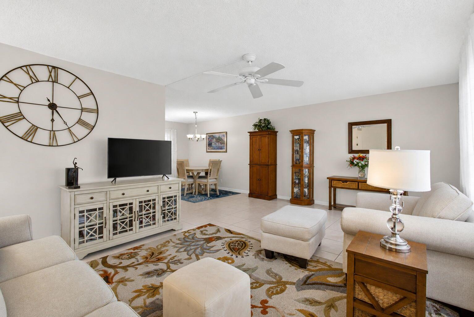 A living room with a large wall clock, a television console, and a dining area — 308 Greenbrier A, West Palm Beach FL 33417, WEST PALM BEACH, FL