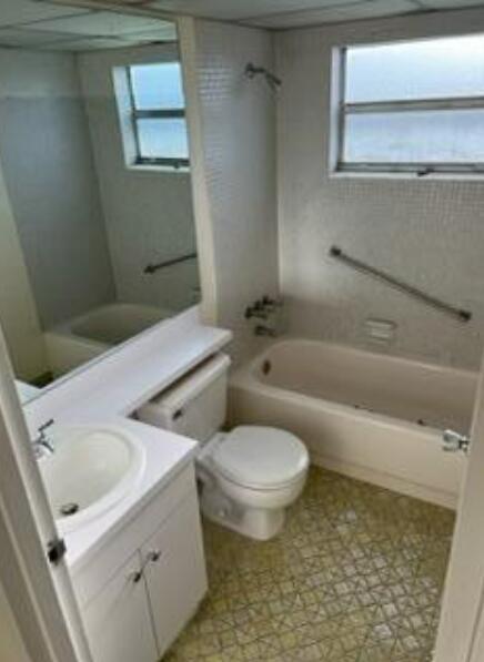 A bathroom features a white vanity, a toilet, and a bathtub with a shower head — 193 Saxony E, Delray Beach FL 33446, DELRAY BEACH, FL
