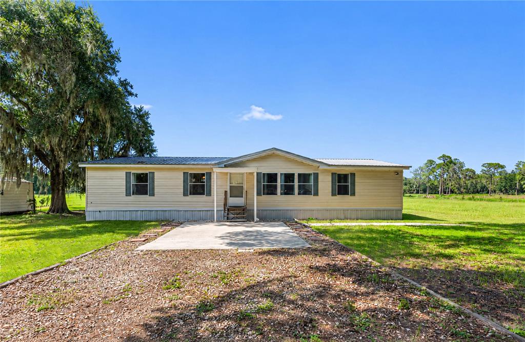 A single-story manufactured home with light siding sits on a grassy lot with trees — 2806 LAWRENCE ROAD, PLANT CITY, FL
