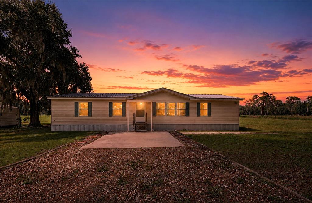 A single-story manufactured home sits on a grassy lot under a vibrant sunset sky — 2806 LAWRENCE ROAD, PLANT CITY, FL