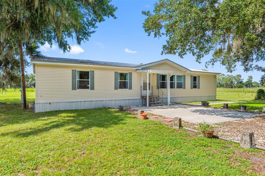 A single-story manufactured home with light yellow siding sits on a grassy lot with trees — 2806 LAWRENCE ROAD, PLANT CITY, FL