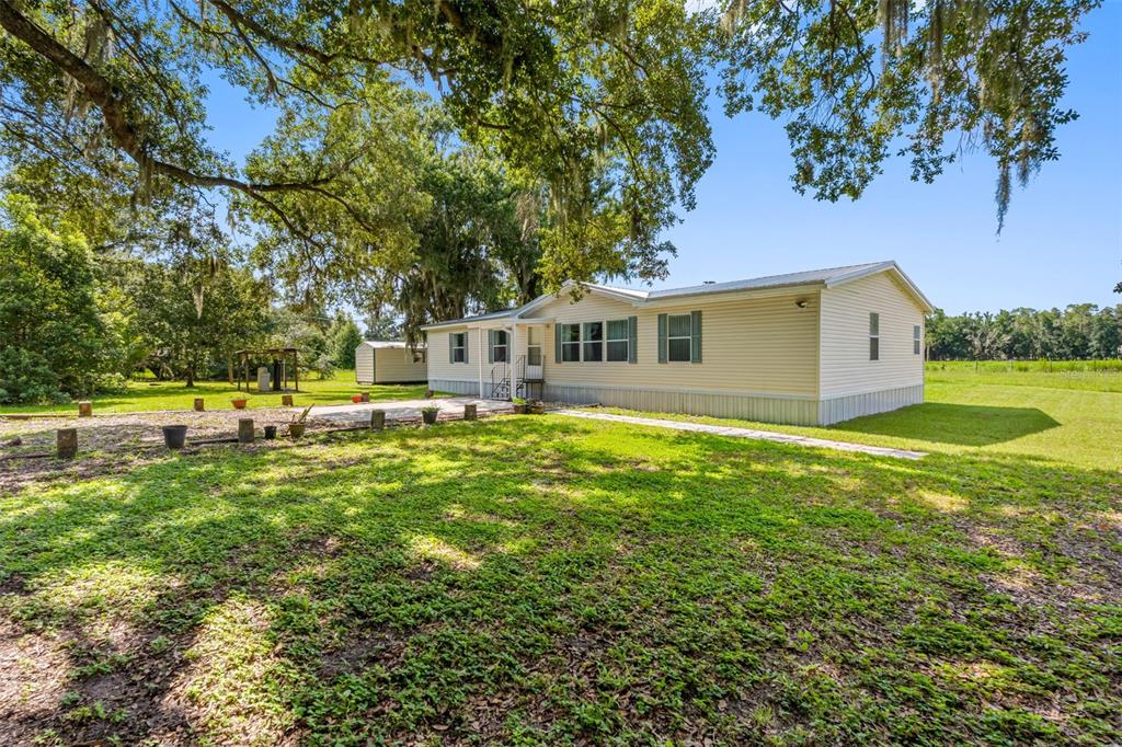 A light-colored manufactured home sits on a grassy lot under large, moss-draped oak trees — 2806 LAWRENCE ROAD, PLANT CITY, FL