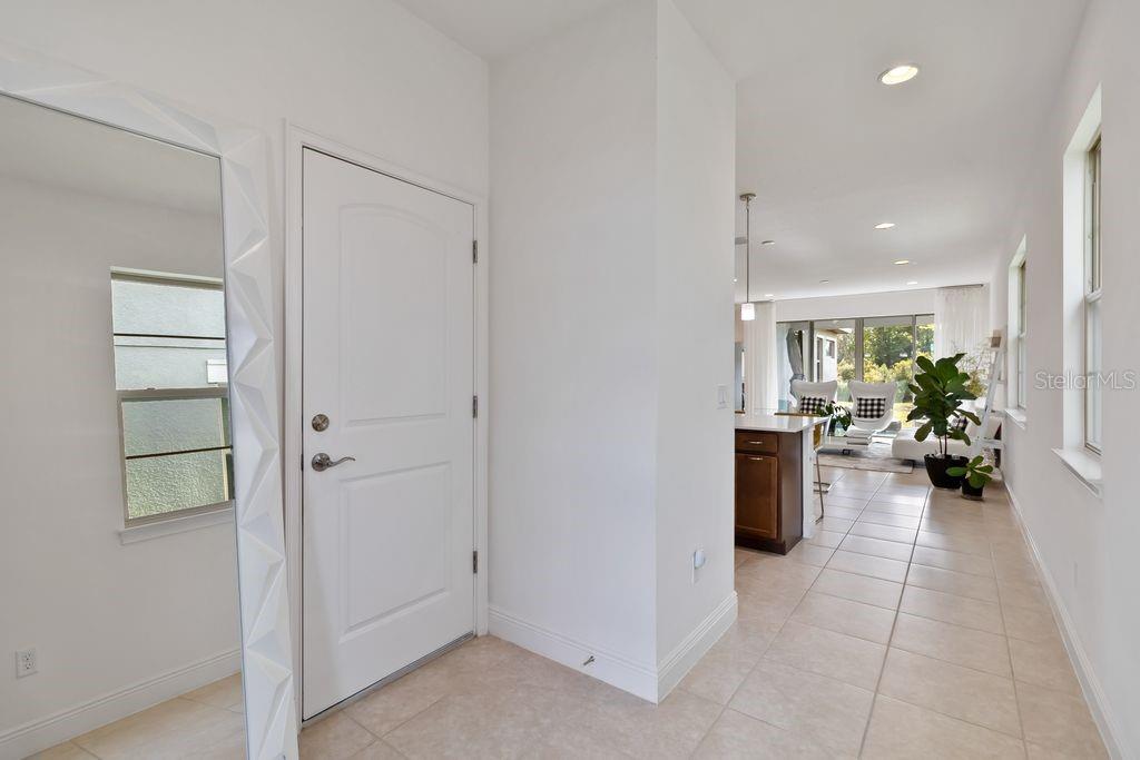 A bright entryway with tile flooring leads into an open-concept kitchen and living area — 3212 OXBOW COURT, HARMONY, FL