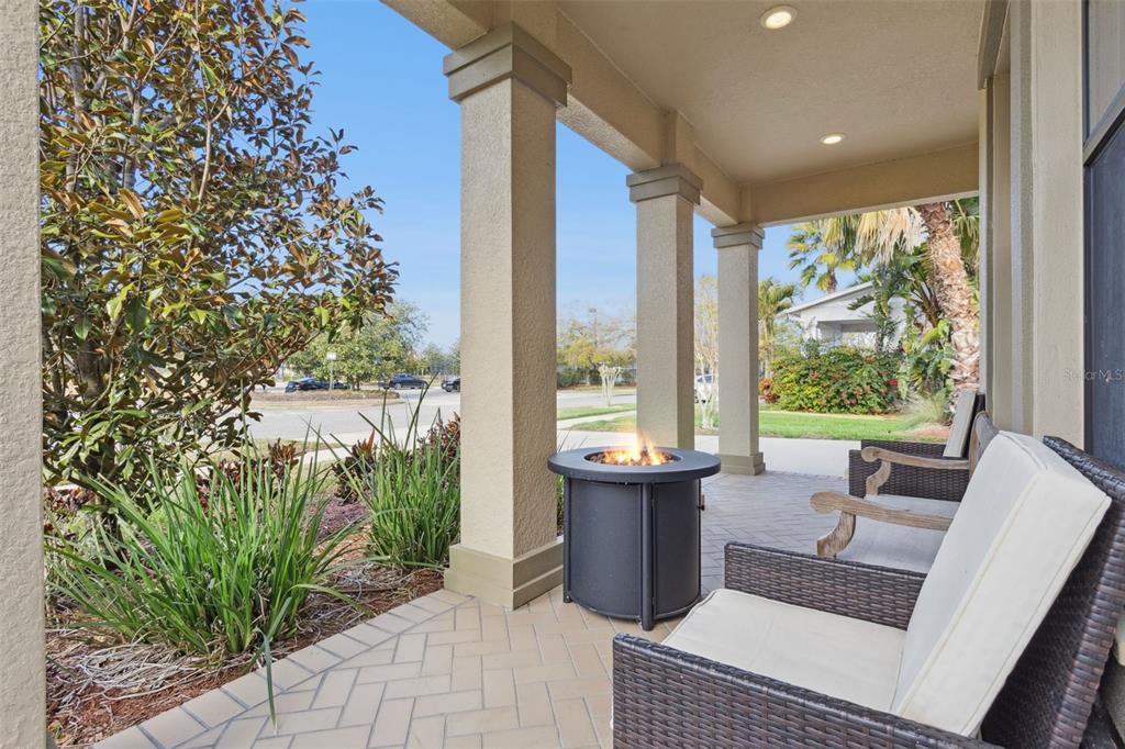 A covered patio features a fire pit, wicker chairs, and a herringbone-patterned tile floor — 8816 SHADY PAVILLION COURT, LAND O LAKES, FL