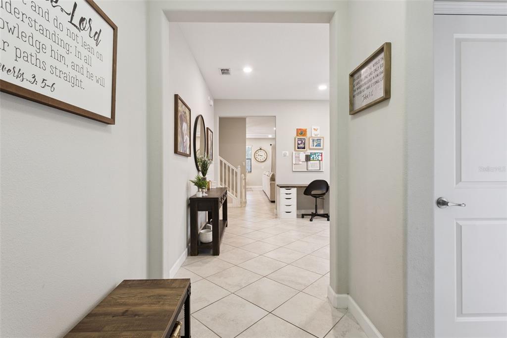 A hallway with tile flooring leads to an office area and a staircase — 8816 SHADY PAVILLION COURT, LAND O LAKES, FL