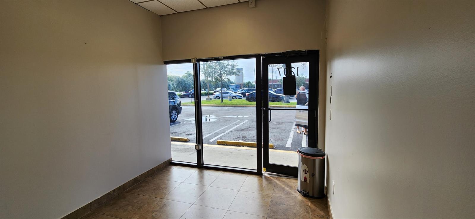 An empty commercial space features tile flooring, beige walls, and a glass storefront entrance — 1207 S Powerline Road, Pompano Beach FL 33069, POMPANO BEACH, FL