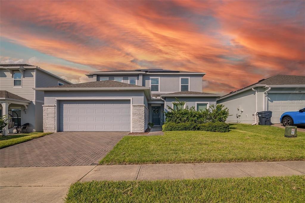 A two-story suburban house with a gray exterior, stone accents, and a paved driveway — 548 OGELTHORPE DRIVE, DAVENPORT, FL
