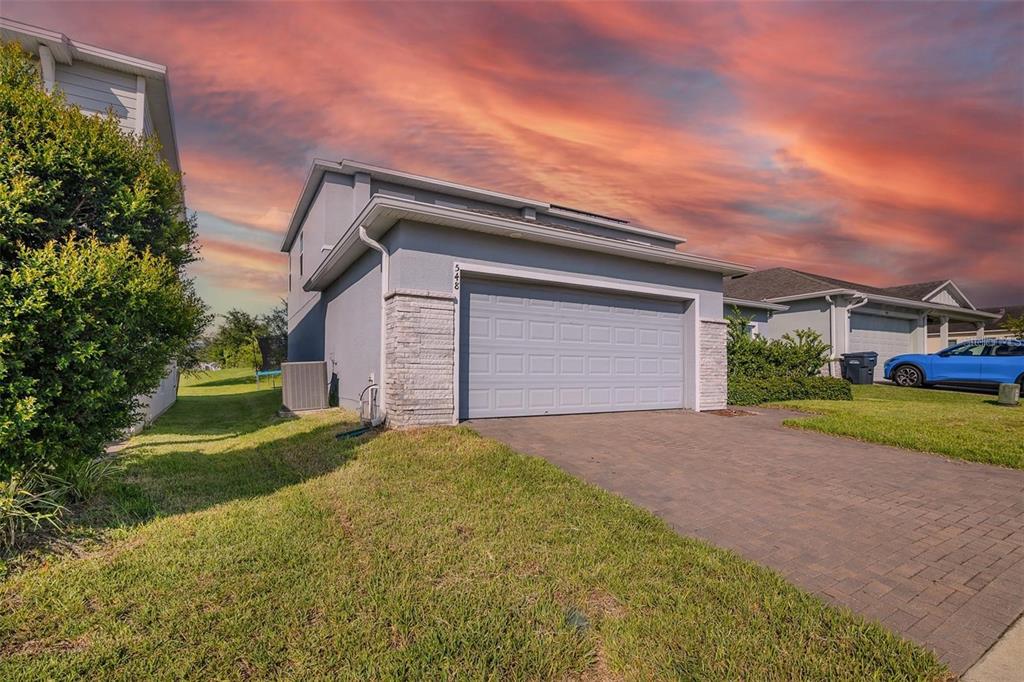 A two-story house exterior featuring a gray garage, stone accents, and a paved driveway — 548 OGELTHORPE DRIVE, DAVENPORT, FL