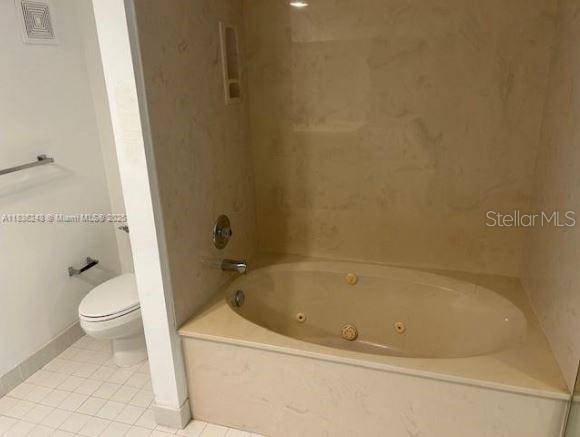 A bathroom features a white toilet and a beige jetted soaking tub with marble-style surround — 3503 OAKS WAY UNIT 212, POMPANO BEACH, FL