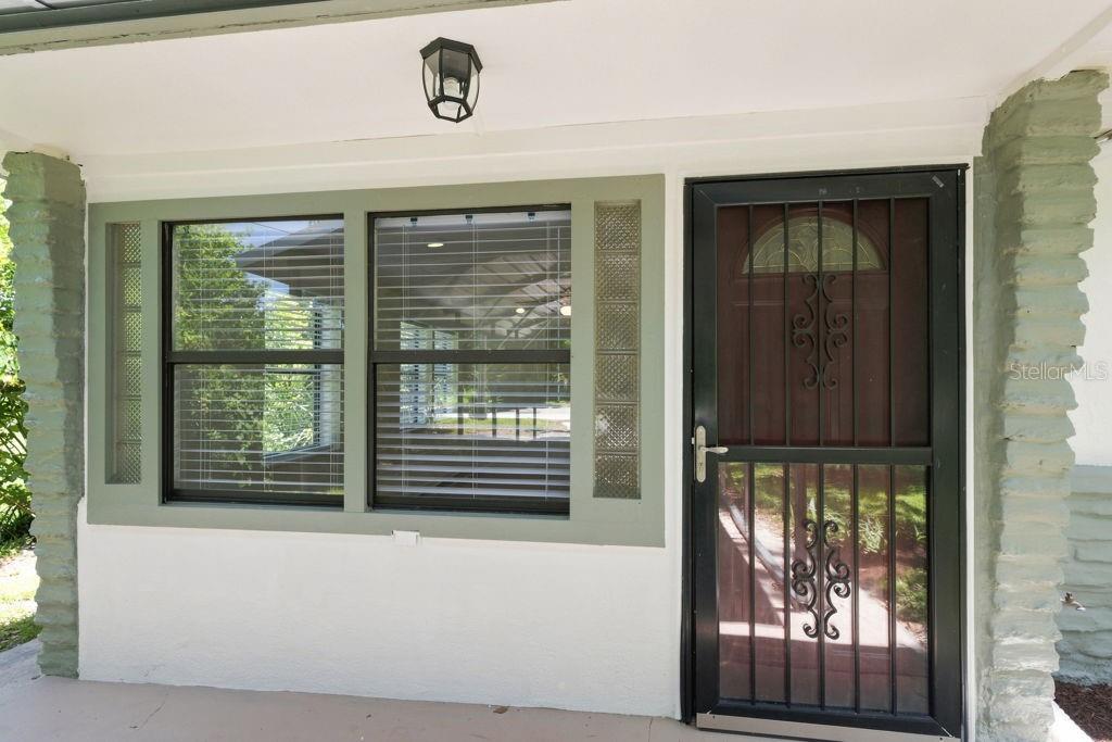 A front porch features a glass-paneled door with a security gate and large windows — 7810 CHAPEL AVENUE, PORT RICHEY, FL