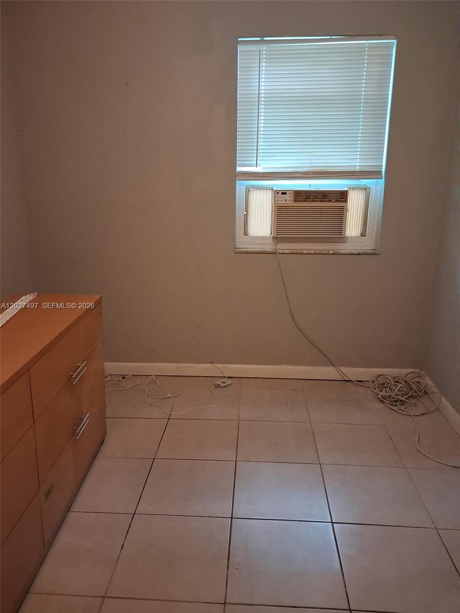 A bedroom with light-colored tile flooring, a window air conditioning unit, and a wooden dresser — 1800 Pinehurst Dr # 1, West Palm Beach FL 33407, WEST PALM BEACH, FL