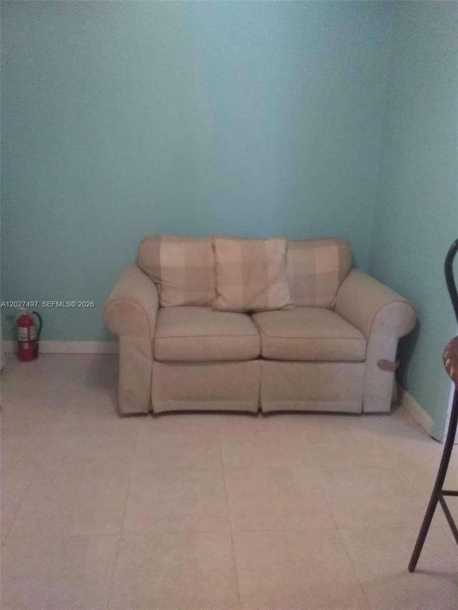 A light-colored loveseat sits against a light blue wall on a tiled floor — 1800 Pinehurst Dr # 1, West Palm Beach FL 33407, WEST PALM BEACH, FL