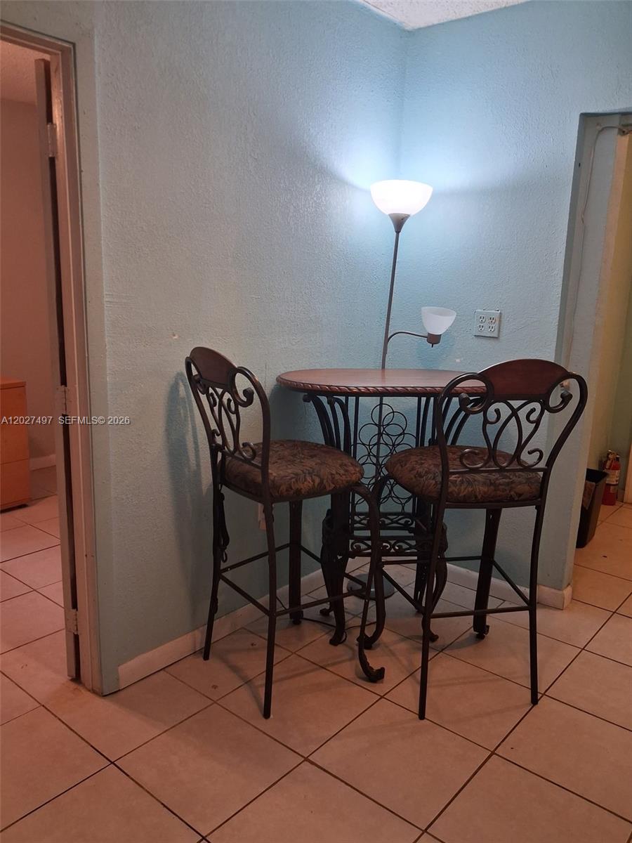 A small bistro table with two metal chairs sits against a light blue wall — 1800 Pinehurst Dr # 1, West Palm Beach FL 33407, WEST PALM BEACH, FL