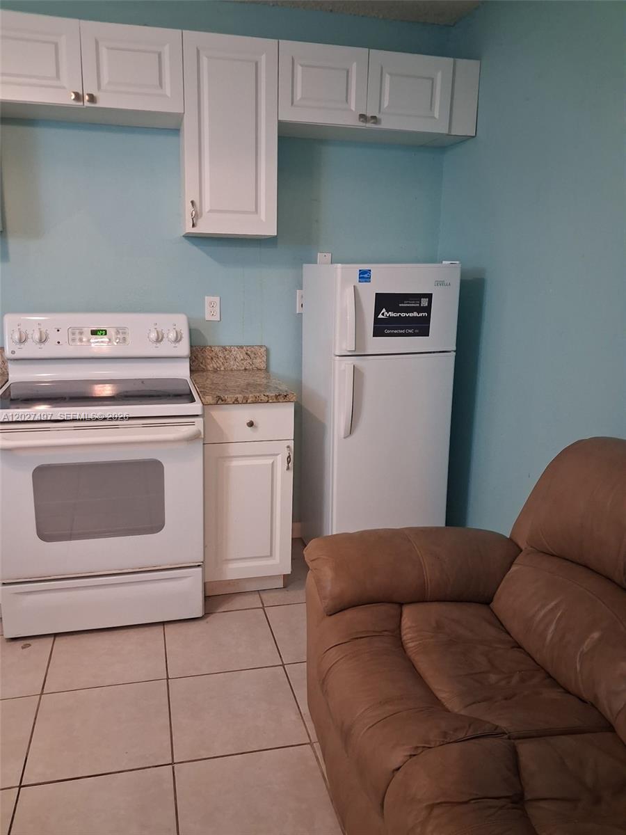 A kitchen features white cabinets, a white stove, a refrigerator, and a brown sofa — 1800 Pinehurst Dr # 1, West Palm Beach FL 33407, WEST PALM BEACH, FL