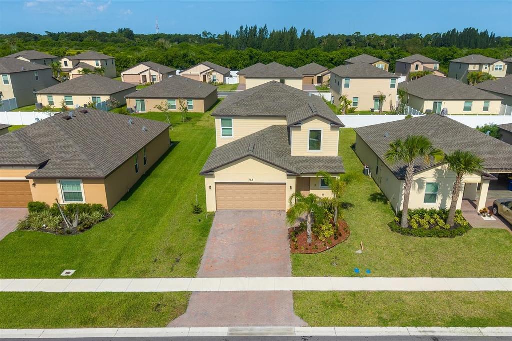 An aerial view shows a two-story suburban house with a paved driveway and green lawn — 763 CARLYLE WAY, FORT PIERCE, FL