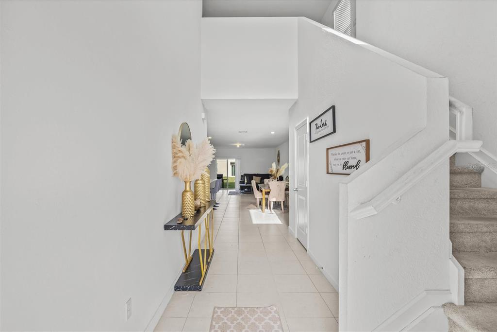 A bright entryway with tile flooring leads to a dining area and staircase with carpet — 763 CARLYLE WAY, FORT PIERCE, FL