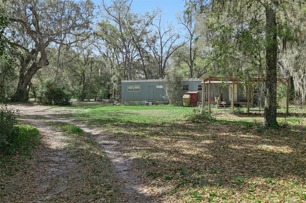 A single-story mobile home sits on a grassy lot surrounded by trees with hanging moss — 15527 TROUSDALE STREET, CLERMONT, FL