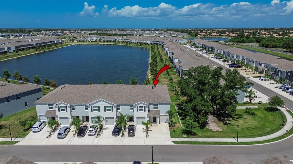An aerial view shows a multi-unit townhouse building with a lake in the background — 331 MANGROVE SHADE CIRCLE, APOLLO BEACH, FL