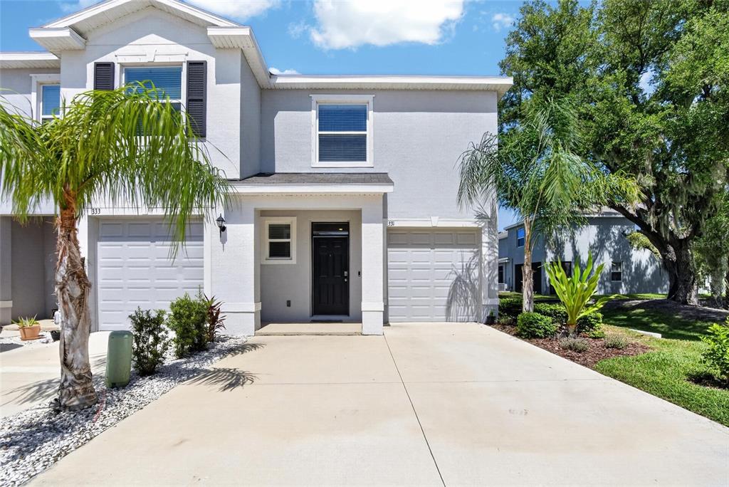 A two-story townhouse with a gray stucco exterior, a black front door, and a concrete driveway — 331 MANGROVE SHADE CIRCLE, APOLLO BEACH, FL