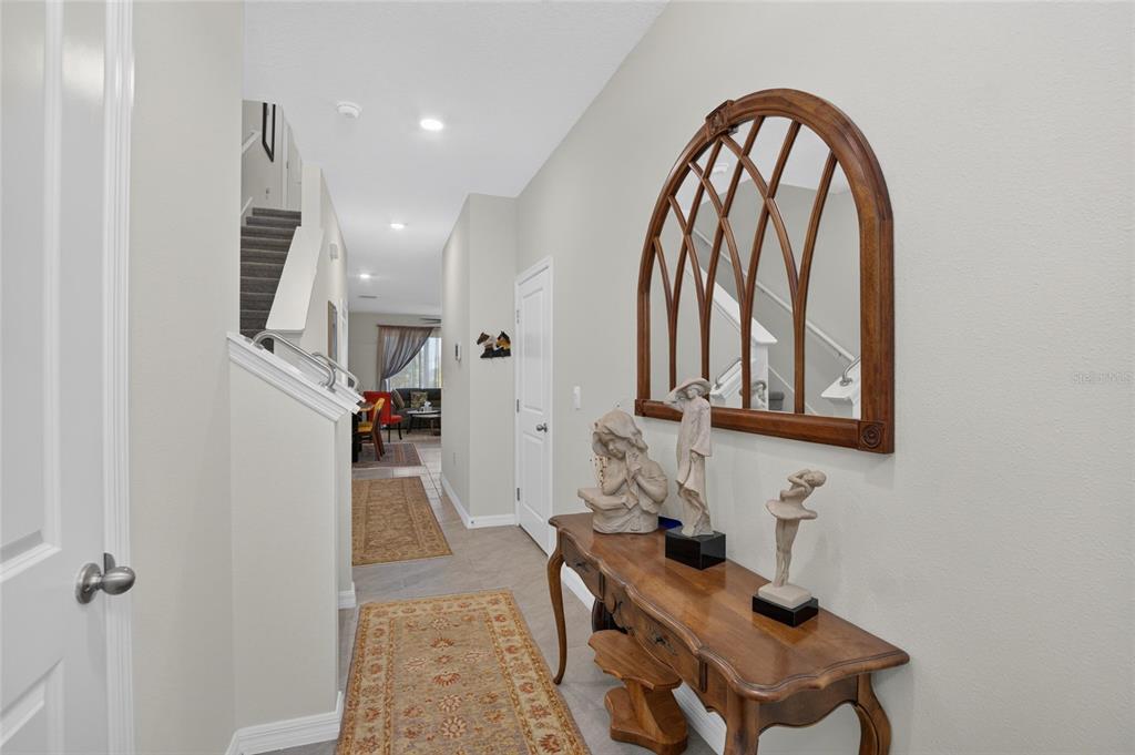 A hallway features a wooden console table with statues, a large arched mirror, and stairs — 331 MANGROVE SHADE CIRCLE, APOLLO BEACH, FL