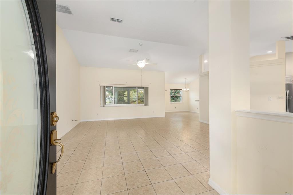 An open-concept living area features light-colored tile flooring, vaulted ceilings, and a ceiling fan — 8601 SW 60TH CIRCLE, OCALA, FL