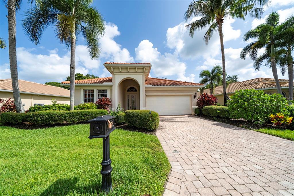 A single-story house with a tiled roof, arched entryway, and a paved driveway — 14073 LAVANTE COURT, BONITA SPRINGS, FL