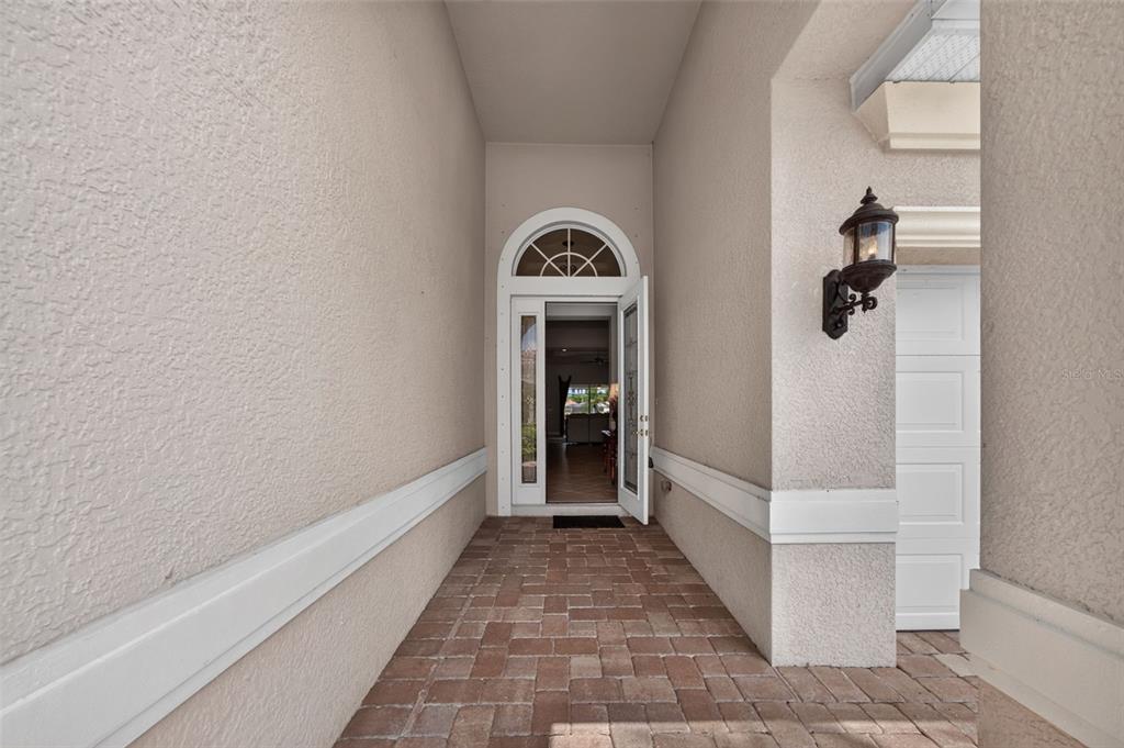 A paved entryway leads to an open front door with a decorative arched transom window — 14073 LAVANTE COURT, BONITA SPRINGS, FL