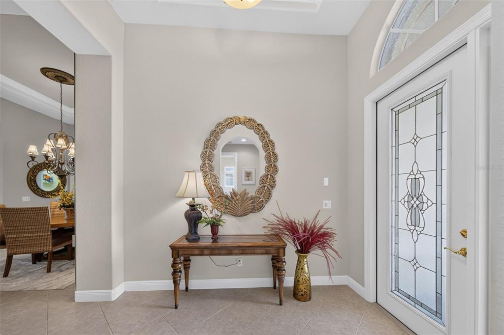 An entryway features a console table, a decorative mirror, and a glass-paneled front door — 14073 LAVANTE COURT, BONITA SPRINGS, FL