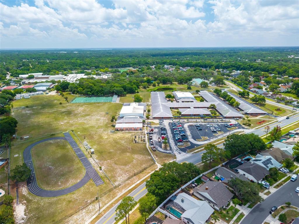 An aerial view shows a school campus with a track, sports fields, and parking lots — 759 TOMLINSON TERRACE, LAKE MARY, FL