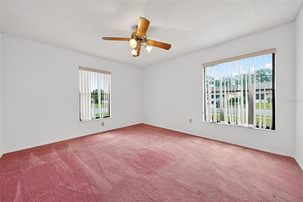 An empty bedroom features pink carpeting, white walls, two windows with blinds, and a ceiling fan — 759 TOMLINSON TERRACE, LAKE MARY, FL