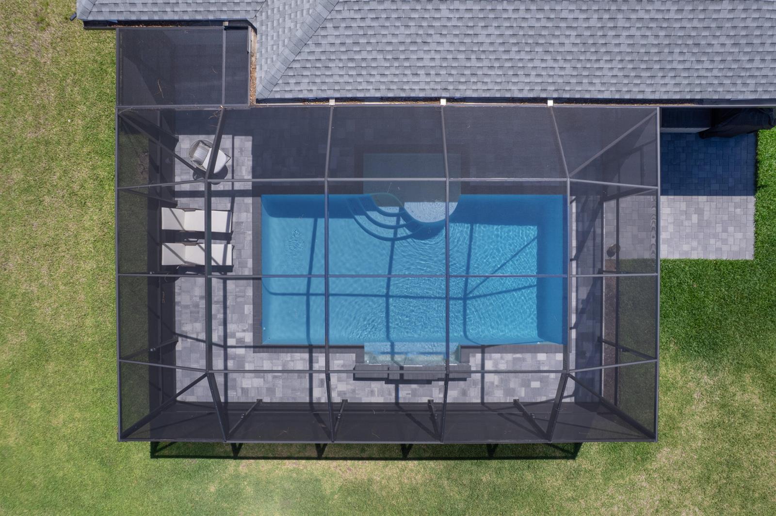 An aerial view of a rectangular swimming pool enclosed by a screened lanai with pavers — 6805 49th Court, Vero Beach FL 32967, VERO BEACH, FL