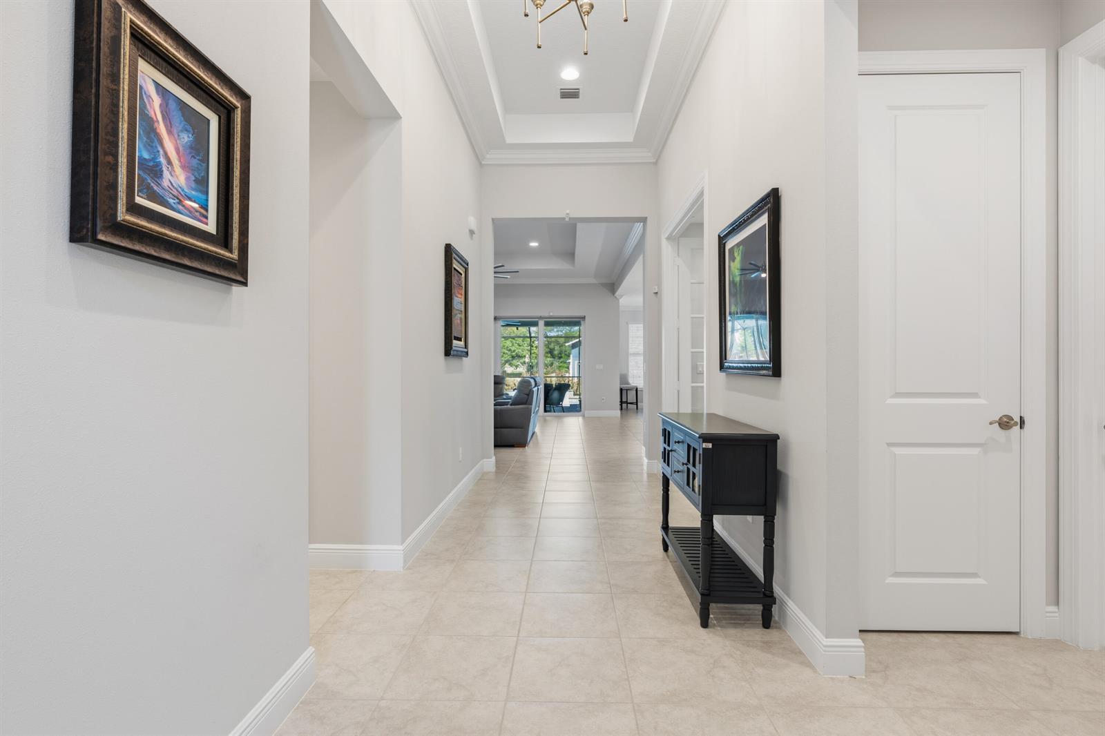 A bright hallway features tile flooring, a tray ceiling, and a black console table — 6805 49th Court, Vero Beach FL 32967, VERO BEACH, FL